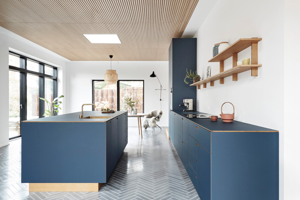 На фото: большая кухня-гостиная в стиле модернизм с синими фасадами, полом из цементной плитки и островом с
