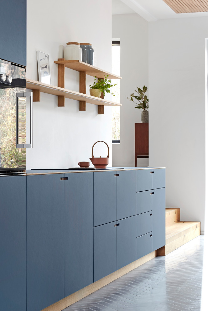 Aménagement d'une grande cuisine ouverte parallèle et encastrable moderne avec un placard à porte plane, des portes de placard bleues, carreaux de ciment au sol, îlot, un sol gris et un plan de travail bleu.