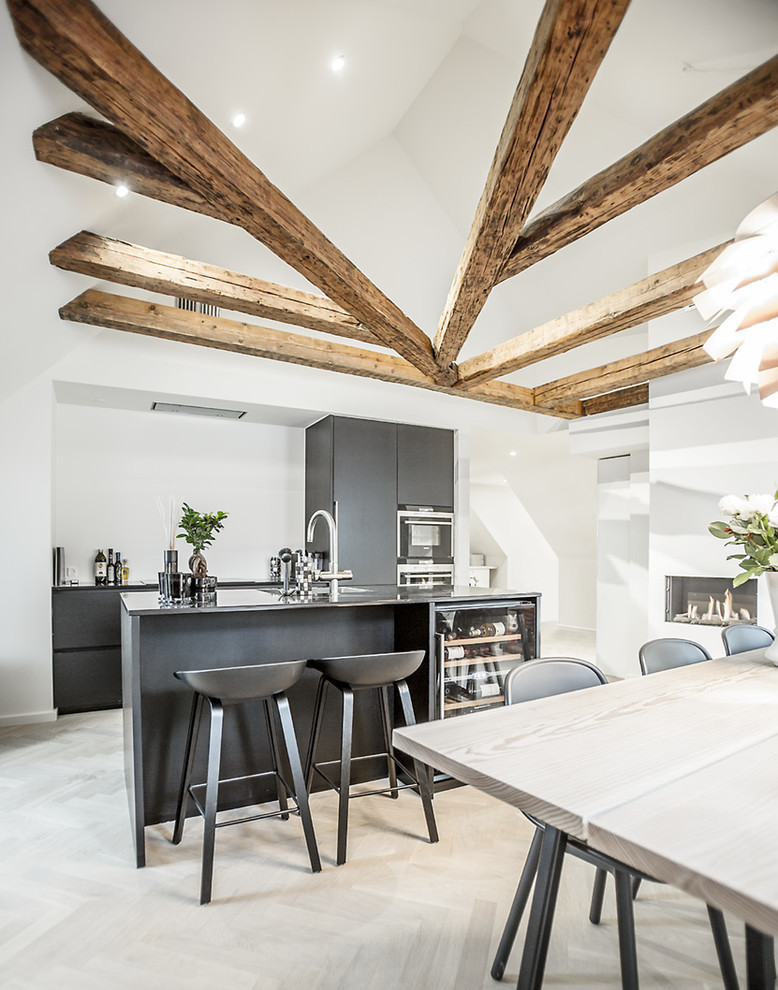 Zweizeilige, Mittelgroße Skandinavische Wohnküche mit flächenbündigen Schrankfronten, schwarzen Schränken, hellem Holzboden und Kücheninsel in Sonstige