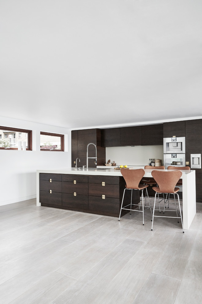 Foto på ett mellanstort minimalistiskt kök, med en dubbel diskho, släta luckor, skåp i mörkt trä, laminatbänkskiva, rostfria vitvaror, ljust trägolv och en köksö