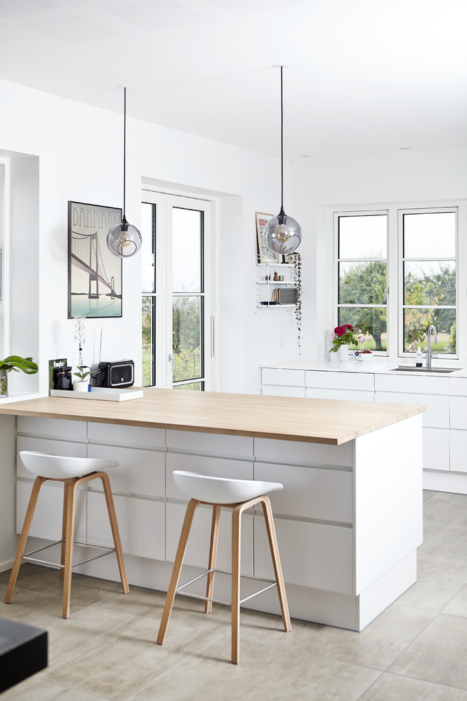 Kitchen - scandinavian beige floor kitchen idea in Aarhus with an undermount sink, flat-panel cabinets, white cabinets, wood countertops, window backsplash and a peninsula