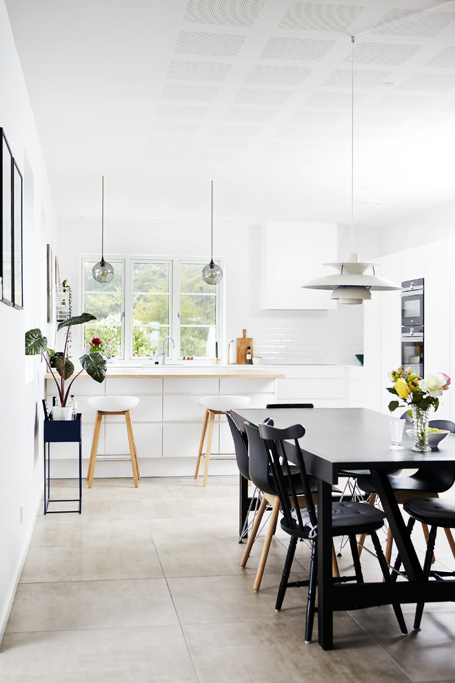 Große Nordische Wohnküche in L-Form mit flächenbündigen Schrankfronten, weißen Schränken, Küchenrückwand in Weiß, Kücheninsel und grauem Boden in Aarhus