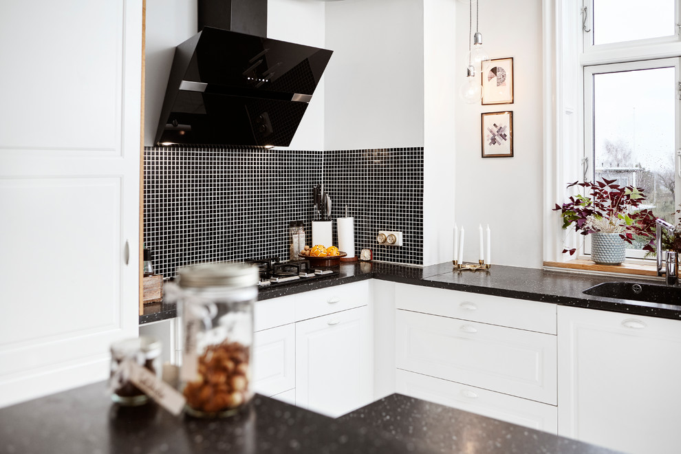 Foto de cocina escandinava pequeña cerrada con armarios con rebordes decorativos, puertas de armario blancas, encimera de granito, salpicadero negro, salpicadero con mosaicos de azulejos y península