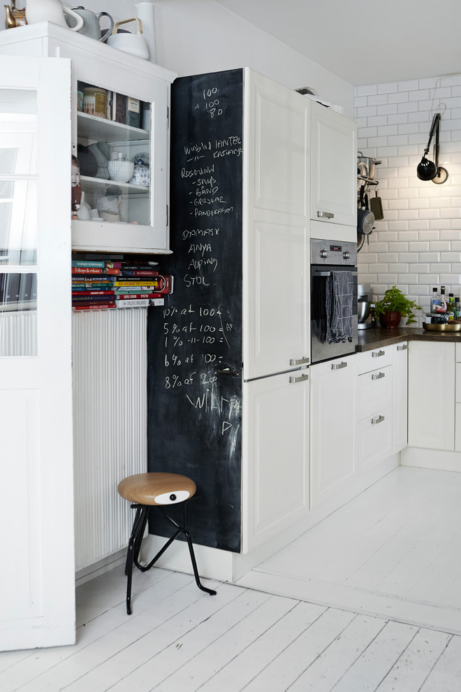 Exempel på ett skandinaviskt kök, med luckor med upphöjd panel, vita skåp, vitt stänkskydd, stänkskydd i tunnelbanekakel och målat trägolv