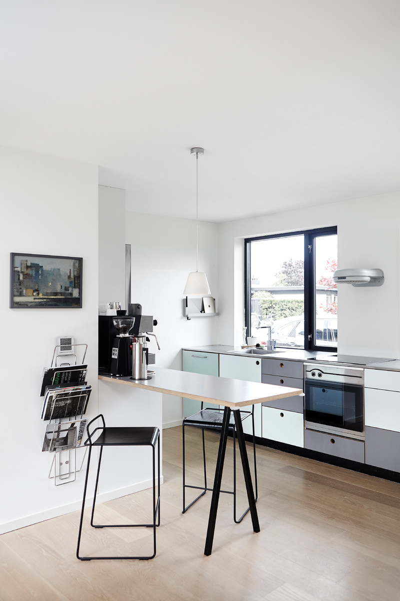 Einzeilige, Mittelgroße Moderne Wohnküche ohne Insel mit flächenbündigen Schrankfronten, Küchengeräten aus Edelstahl und hellem Holzboden in Aarhus