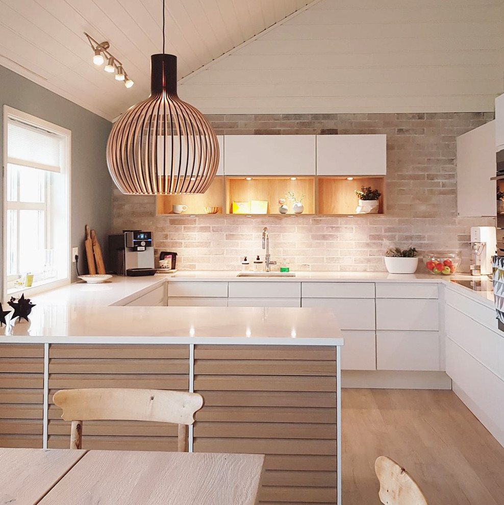 Idéer för att renovera ett nordiskt vit vitt kök, med en undermonterad diskho, släta luckor, vita skåp, beige stänkskydd, stänkskydd i tegel, integrerade vitvaror, mellanmörkt trägolv, en halv köksö och beiget golv