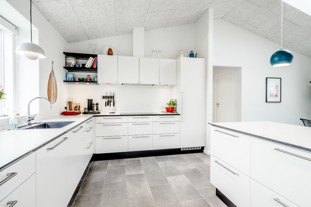 Foto på ett nordiskt kök, med en enkel diskho, släta luckor, vita skåp, vitt stänkskydd, integrerade vitvaror och en köksö