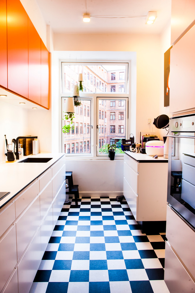 Zweizeilige, Kleine Moderne Küche ohne Insel mit flächenbündigen Schrankfronten, orangefarbenen Schränken, Einbauwaschbecken, Laminat-Arbeitsplatte, Küchengeräten aus Edelstahl und Linoleum in Aalborg