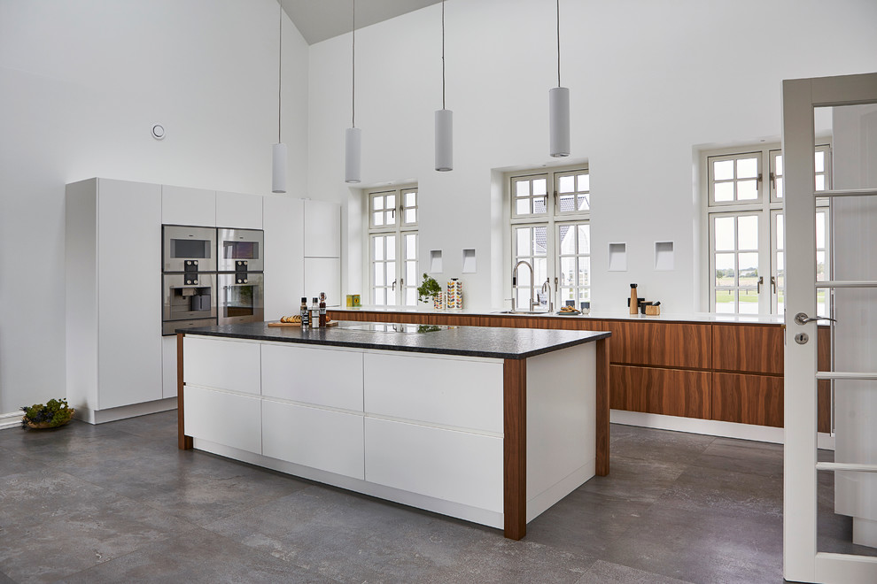 Foto di un cucina con isola centrale nordico con lavello sottopiano, ante lisce, ante in legno scuro, elettrodomestici in acciaio inossidabile e pavimento in cemento