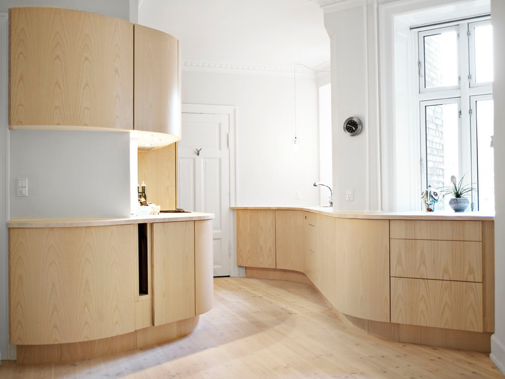 На фото: отдельная, параллельная кухня среднего размера в скандинавском стиле с светлыми деревянными фасадами, деревянной столешницей, техникой под мебельный фасад и светлым паркетным полом без острова с