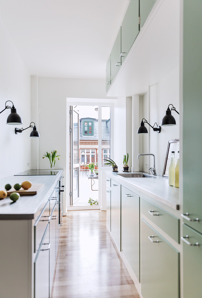 Идея дизайна: параллельная кухня в скандинавском стиле с плоскими фасадами, зелеными фасадами и паркетным полом среднего тона без острова