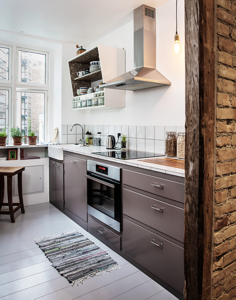 Свежая идея для дизайна: прямая кухня в скандинавском стиле с обеденным столом, плоскими фасадами, серыми фасадами, белым фартуком, деревянным полом и серым полом - отличное фото интерьера