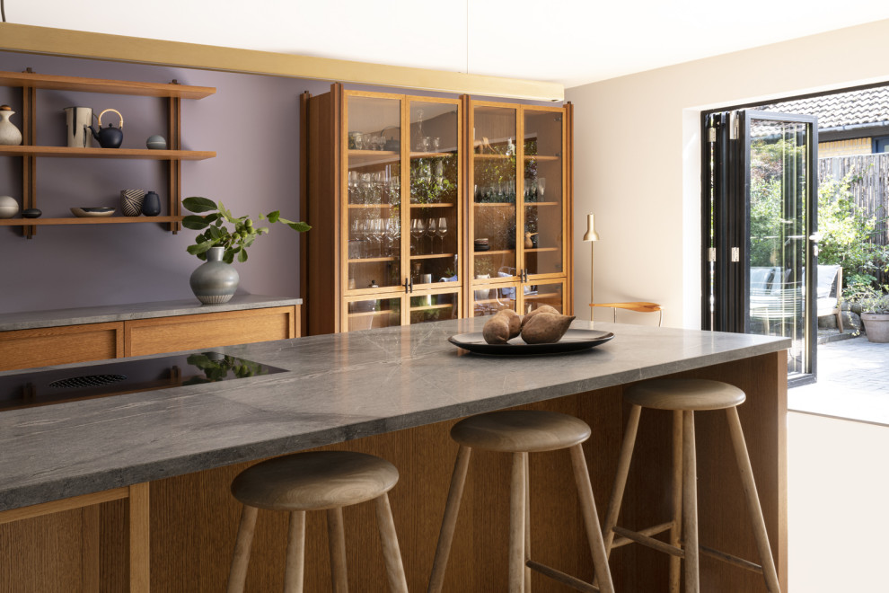Esempio di una cucina moderna di medie dimensioni con ante con bugna sagomata, ante in legno bruno, top in quarzite, pavimento in legno massello medio, penisola, pavimento marrone e top grigio