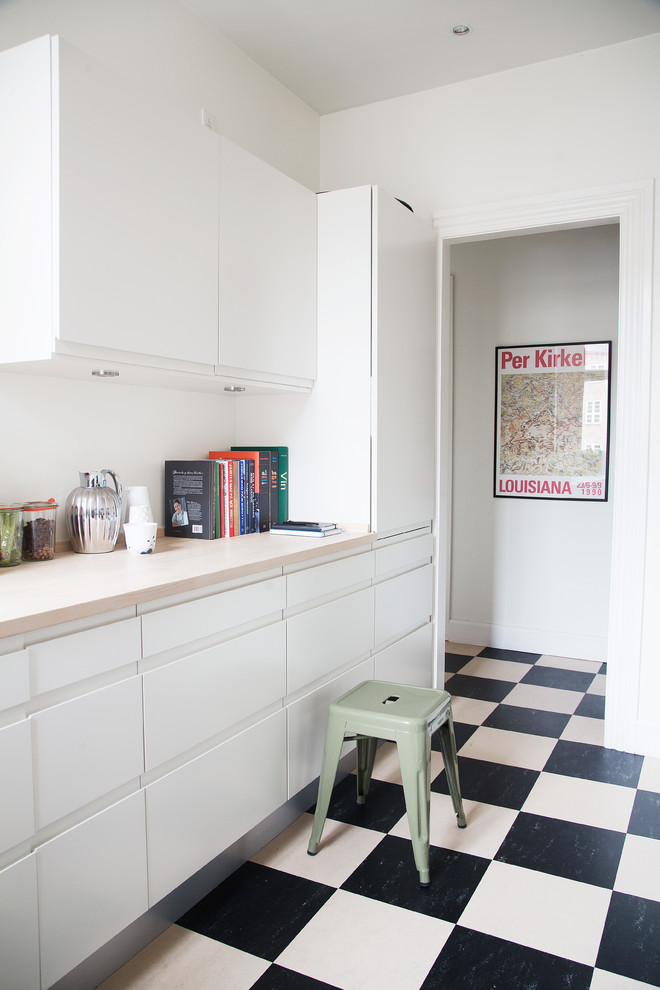 Foto på ett avskilt, litet minimalistiskt linjärt kök, med släta luckor, vita skåp, träbänkskiva och linoleumgolv