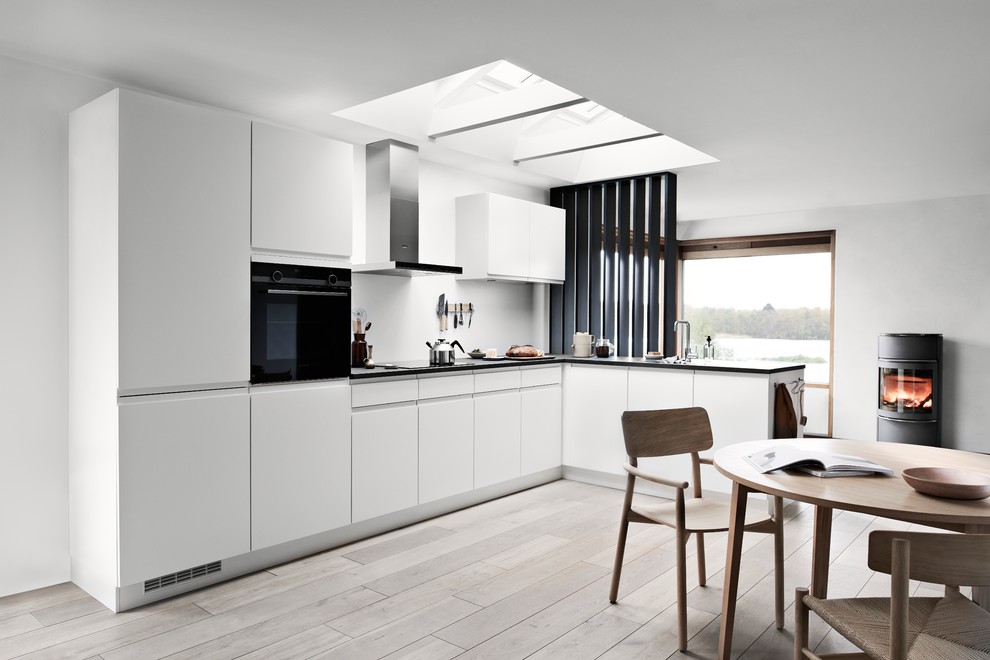 Стильный дизайн: кухня в скандинавском стиле с одинарной мойкой, плоскими фасадами, белыми фасадами, столешницей из ламината и черной столешницей - последний тренд