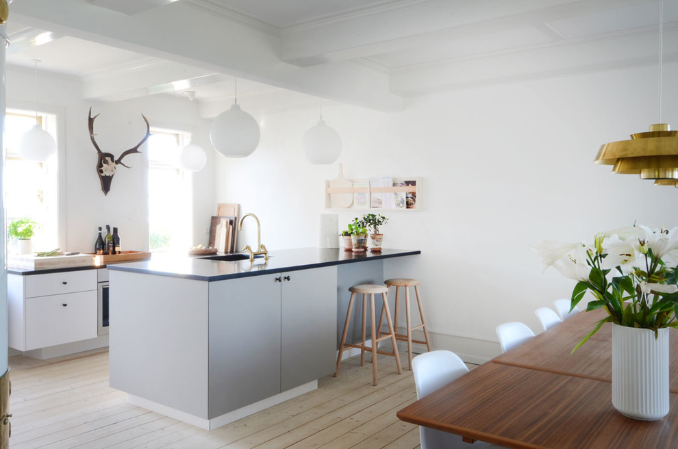 Mittelgroße Skandinavische Küche mit flächenbündigen Schrankfronten, grauen Schränken, hellem Holzboden, Kücheninsel und beigem Boden in Odense