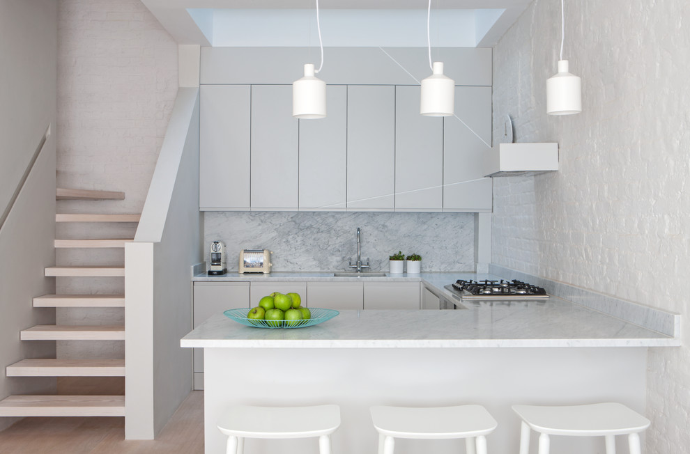 Example of a minimalist single-wall light wood floor and beige floor open concept kitchen design in Copenhagen with flat-panel cabinets, gray cabinets, gray backsplash, a peninsula and gray countertops