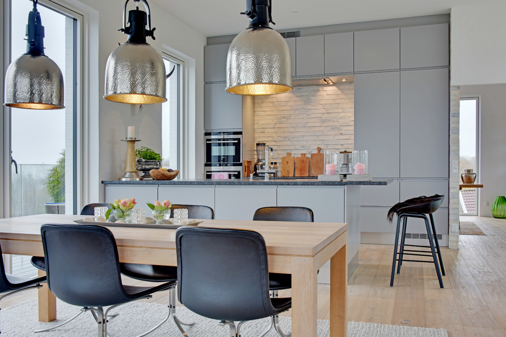 Идея дизайна: кухня в скандинавском стиле с плоскими фасадами, серыми фасадами, мраморной столешницей, фартуком из кирпича, светлым паркетным полом и полуостровом