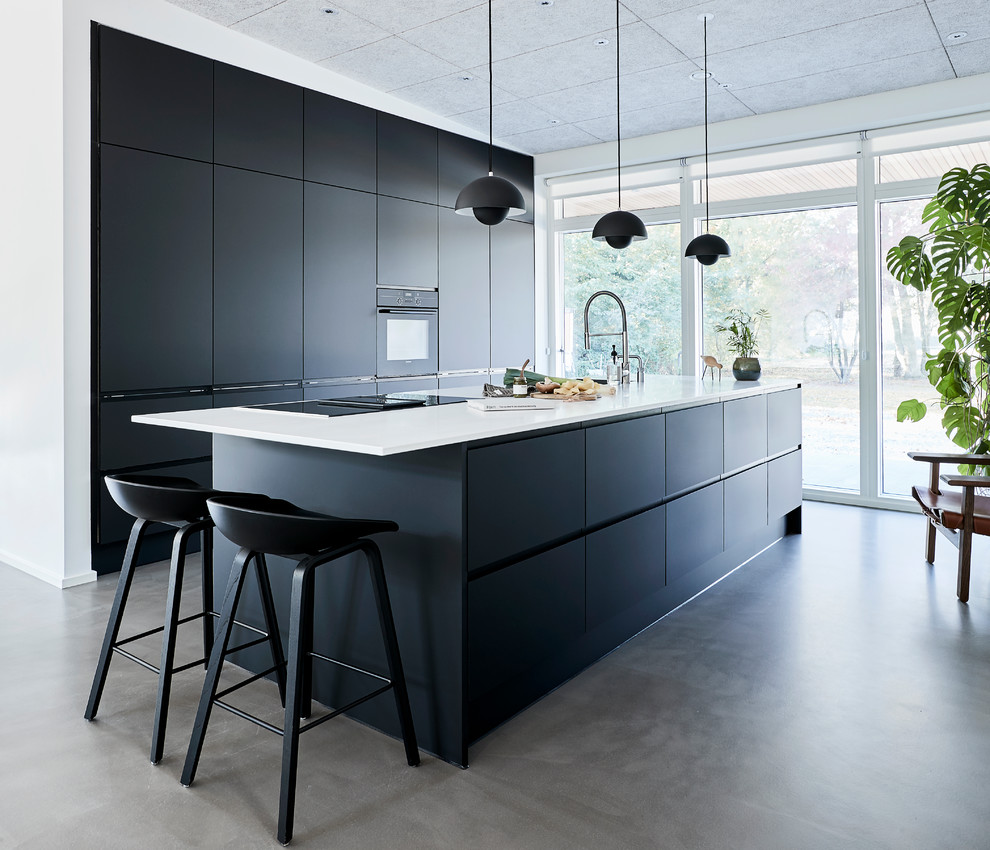 Inspiration for a contemporary concrete floor and gray floor kitchen remodel in Other with flat-panel cabinets, black cabinets, black appliances, an island and white countertops