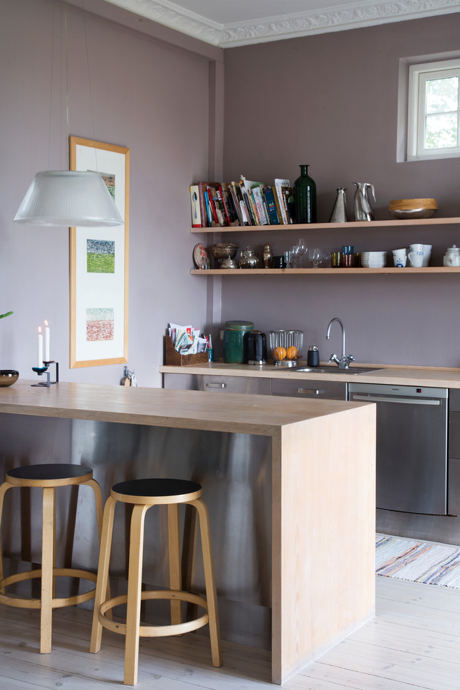 This is an example of a medium sized scandi grey and purple galley enclosed kitchen in Copenhagen with a built-in sink, flat-panel cabinets, stainless steel cabinets, stainless steel appliances, light hardwood flooring, a breakfast bar and wood worktops.