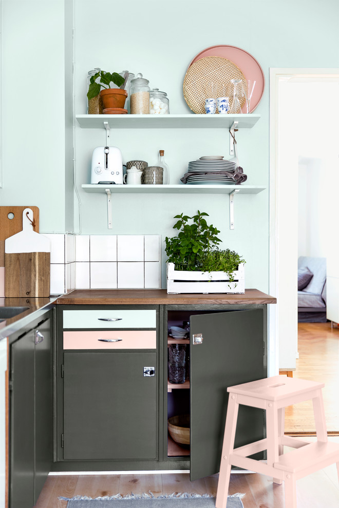 Foto på ett minimalistiskt l-kök, med en nedsänkt diskho, släta luckor, grå skåp, träbänkskiva, vitt stänkskydd och ljust trägolv