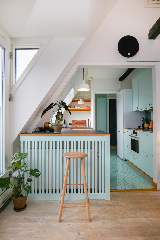コペンハーゲンにある小さな北欧スタイルのおしゃれなペニンシュラキッチン (フラットパネル扉のキャビネット、ターコイズのキャビネット、木材カウンター、ターコイズの床) の写真