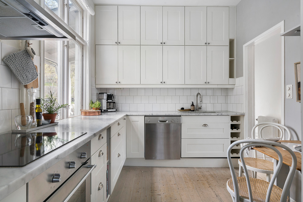 This is an example of a scandi kitchen in Copenhagen with shaker cabinets, white cabinets and marble worktops.