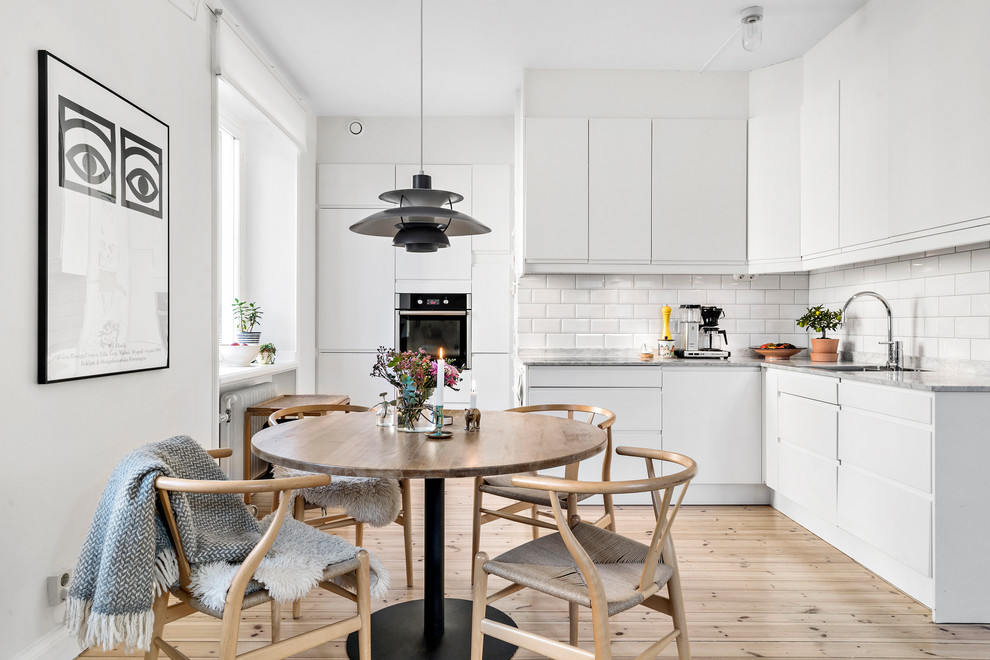 Bild på ett skandinaviskt kök och matrum, med vita skåp, marmorbänkskiva och vitt stänkskydd