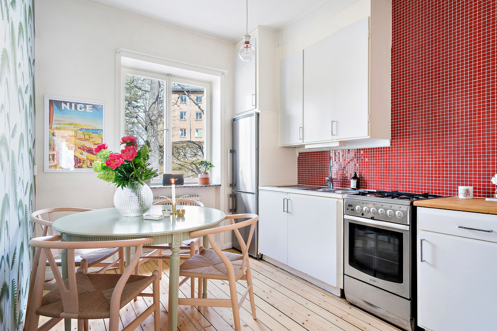 Cette photo montre une cuisine linéaire scandinave avec un plan de travail en bois et une crédence rouge.