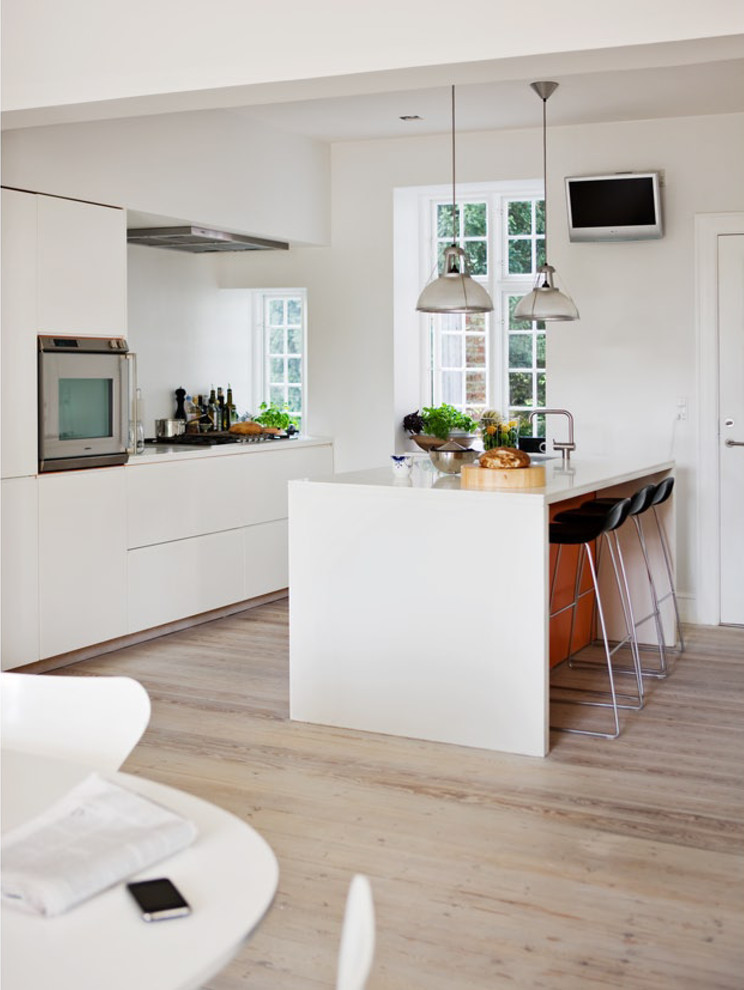 Nordische Küche mit weißen Schränken, hellem Holzboden, Kücheninsel und beigem Boden in Kopenhagen