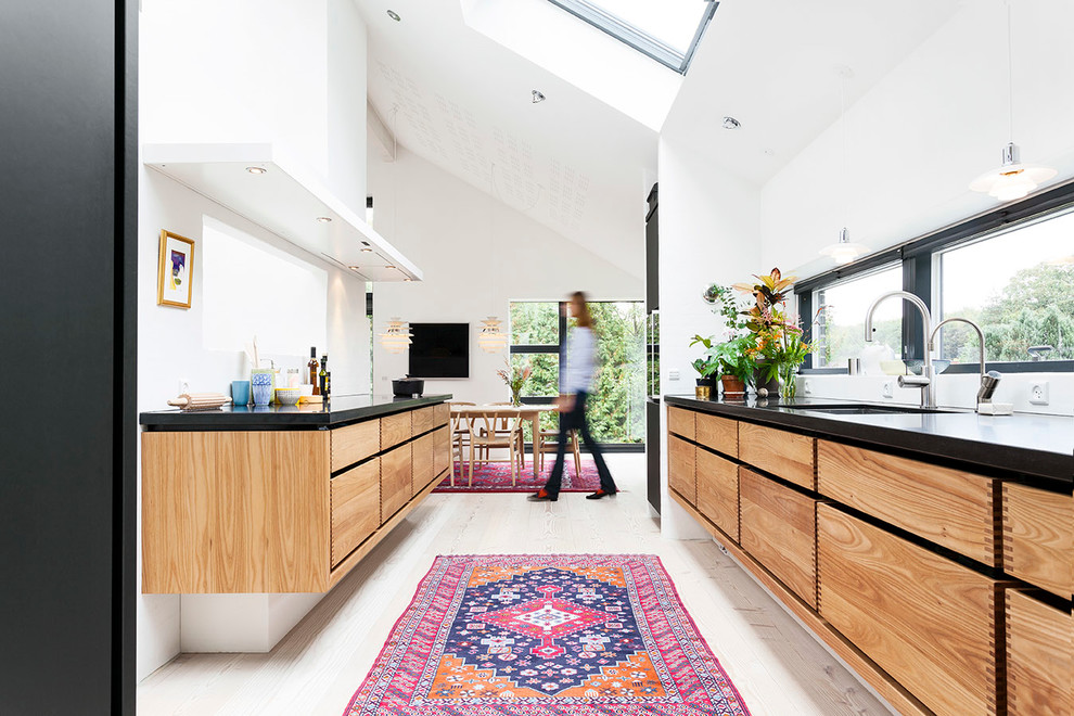 Eat-in kitchen - mid-sized scandinavian galley light wood floor eat-in kitchen idea in Copenhagen with an undermount sink, flat-panel cabinets, paneled appliances, no island and light wood cabinets