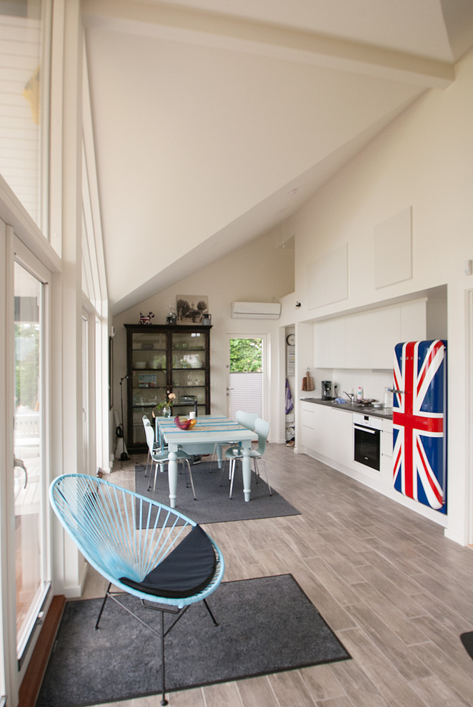 Свежая идея для дизайна: прямая кухня-гостиная среднего размера в современном стиле с коричневым полом, плоскими фасадами и белыми фасадами - отличное фото интерьера