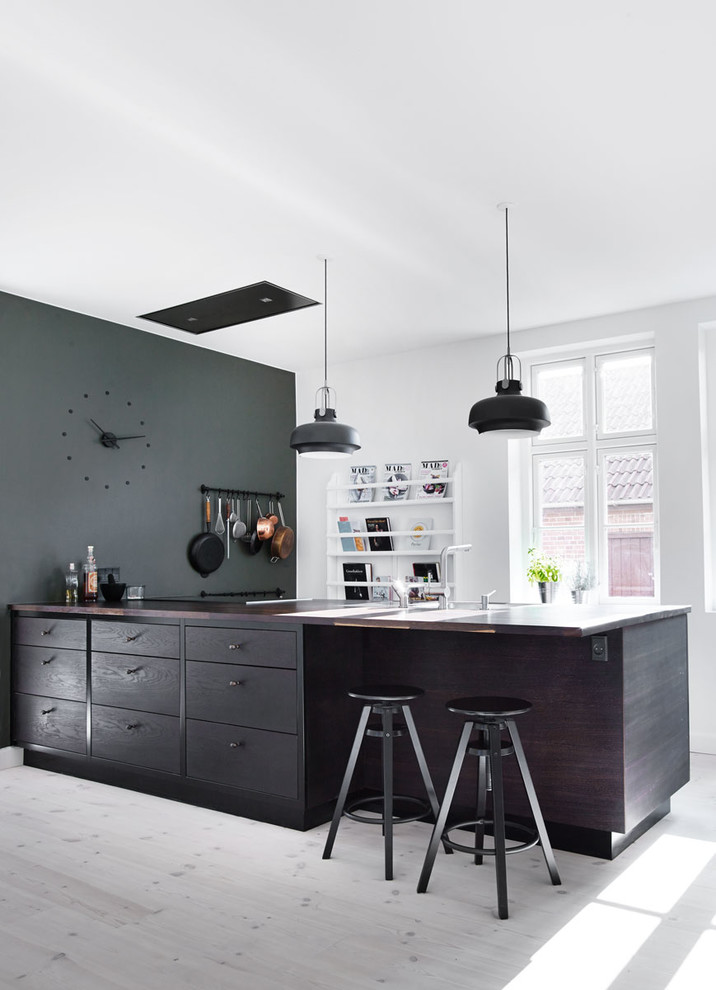 Ejemplo de cocina comedor gris y negra contemporánea grande con armarios con paneles lisos, puertas de armario negras, encimera de madera, suelo de madera clara y una isla