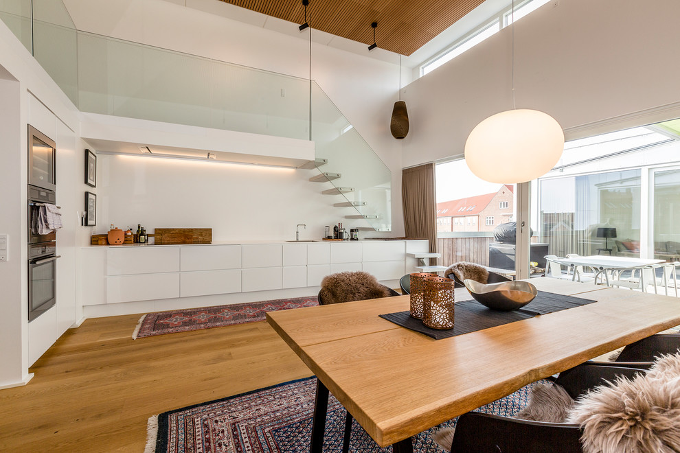Imagen de cocinas en L escandinava sin isla con armarios con paneles lisos, puertas de armario blancas y suelo de madera en tonos medios