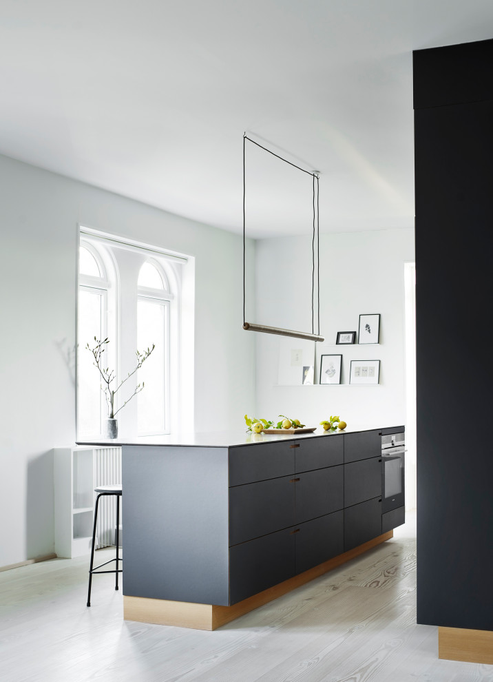 Foto de cocina lineal escandinava de tamaño medio abierta con puertas de armario negras, encimera de mármol y una isla