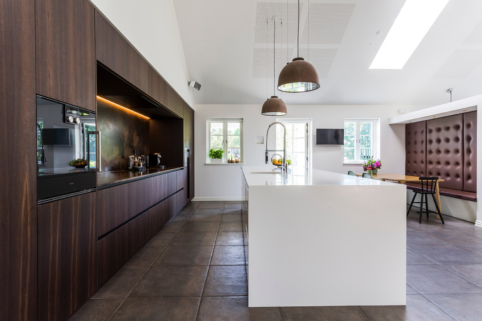На фото: параллельная кухня-гостиная в современном стиле с плоскими фасадами, темными деревянными фасадами, черной техникой и островом