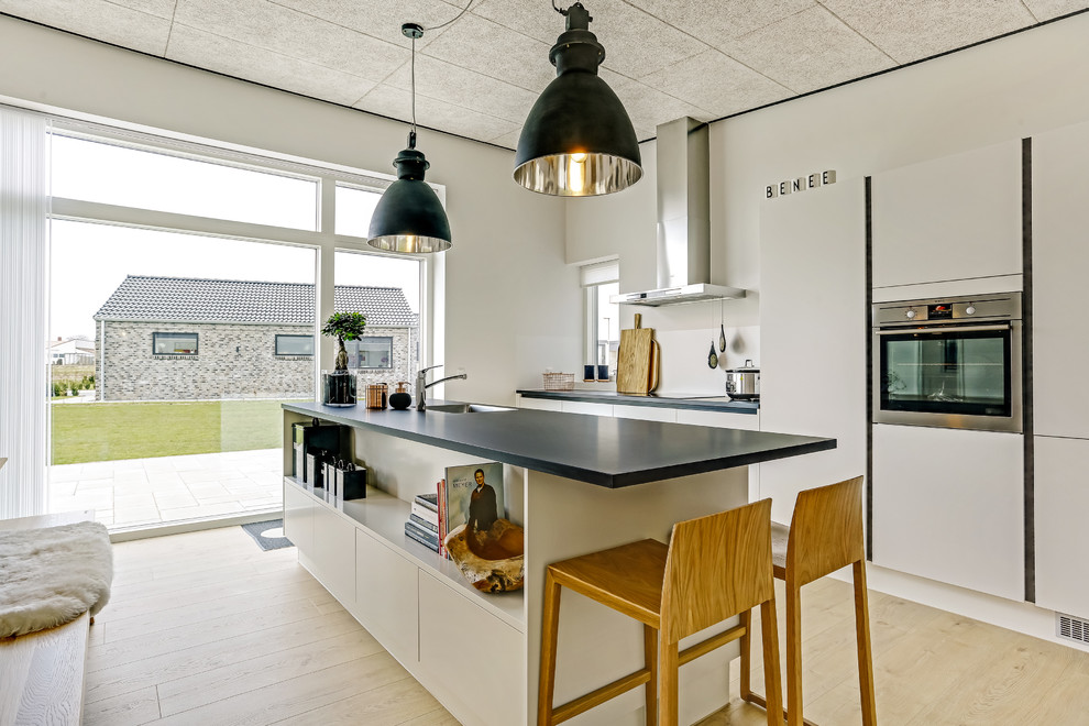 Inspiration pour une cuisine minimaliste avec une crédence blanche, îlot et plan de travail noir.