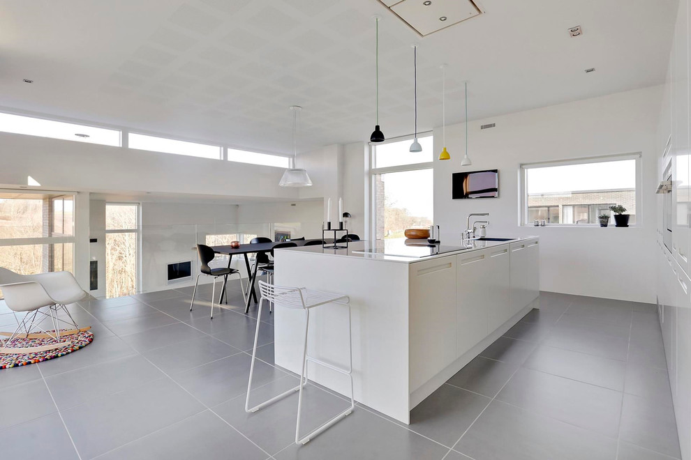 Inspiration for a mid-sized modern galley ceramic tile eat-in kitchen remodel in Esbjerg with a drop-in sink, flat-panel cabinets, white cabinets, laminate countertops and an island