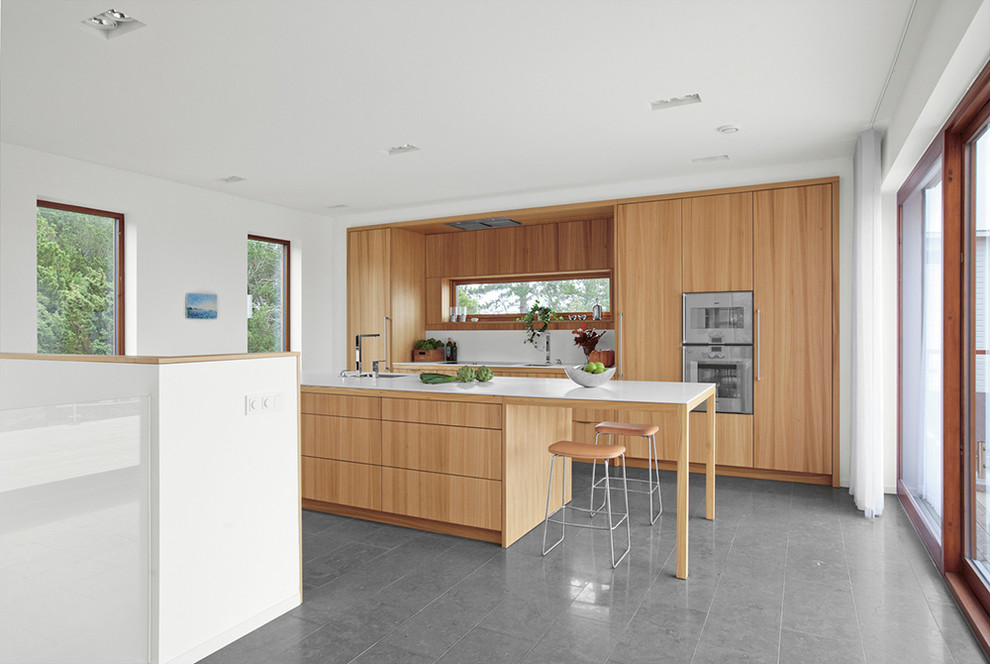 Exemple d'une cuisine parallèle et encastrable scandinave en bois brun de taille moyenne avec un placard à porte plane, îlot et un sol gris.