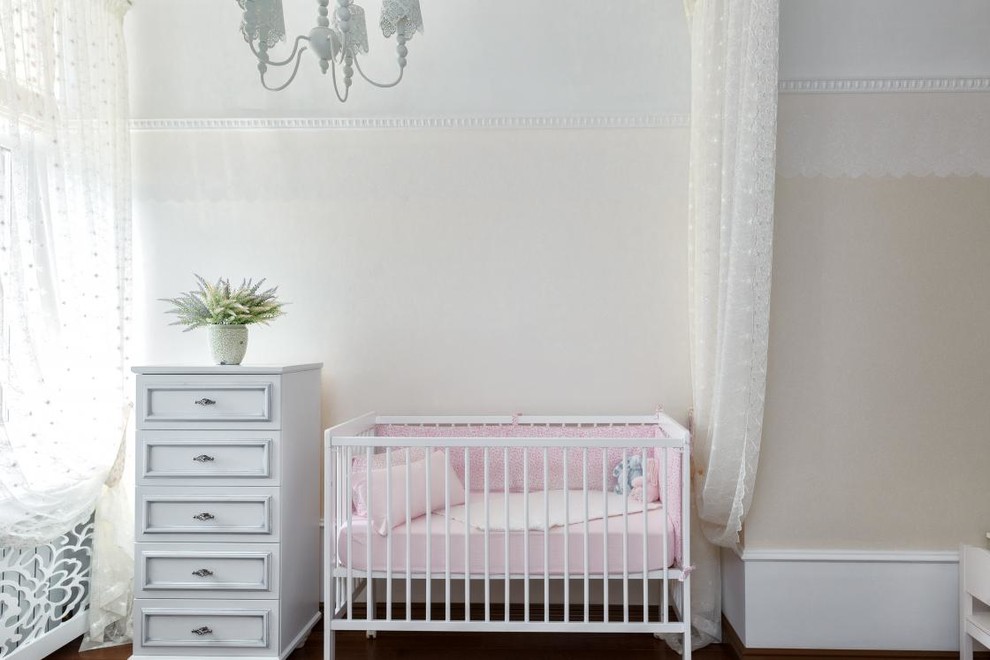 Foto de habitación de bebé niña tradicional de tamaño medio con paredes blancas, suelo de madera oscura y suelo marrón