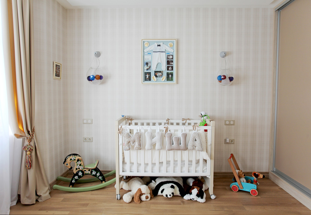 Exemple d'une chambre de bébé garçon tendance avec un mur blanc et un sol en bois brun.
