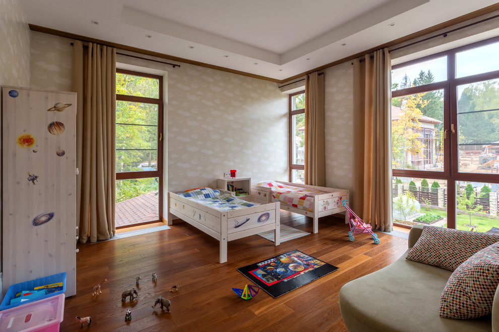 Foto på ett litet könsneutralt babyrum, med beige väggar, mellanmörkt trägolv och brunt golv