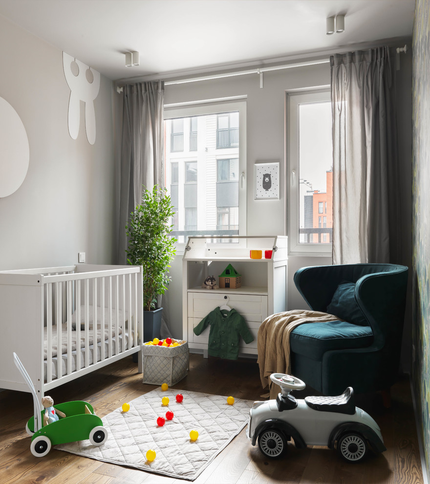 Inspiration pour une petite chambre de bébé neutre design avec un mur gris et un sol en bois brun.