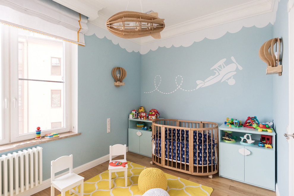 На фото: нейтральная комната для малыша в скандинавском стиле с синими стенами, паркетным полом среднего тона и коричневым полом