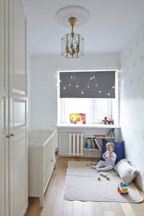 Cette image montre une petite chambre de bébé design avec un mur blanc et parquet clair.