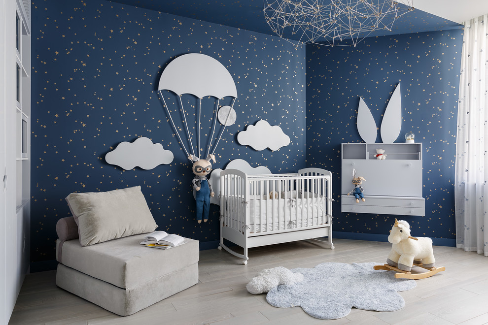 Réalisation d'une chambre de bébé neutre design avec un mur bleu, parquet clair et un sol beige.