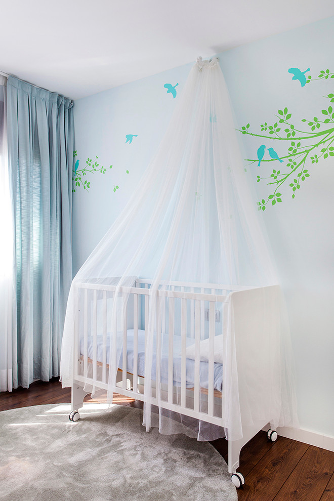 Esempio di una piccola cameretta per neonati neutra classica con pareti blu e parquet scuro