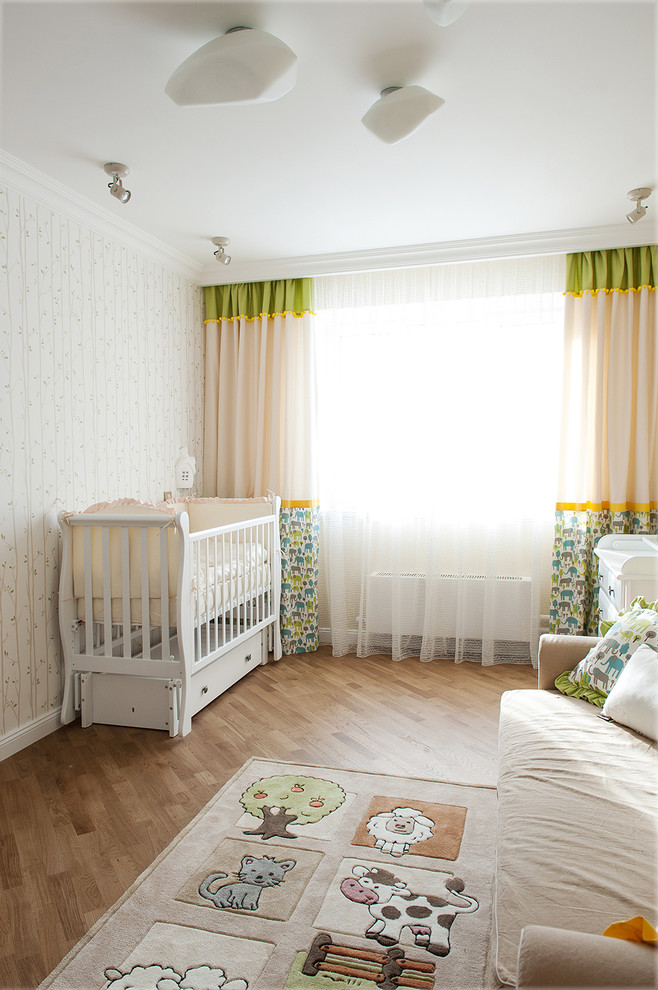Cette photo montre une chambre de bébé tendance avec un mur beige et un sol en bois brun.