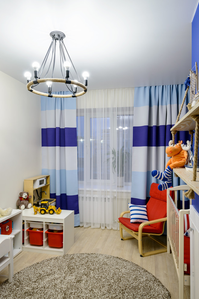 Diseño de habitación de bebé niño actual de tamaño medio con paredes azules, suelo laminado y suelo beige