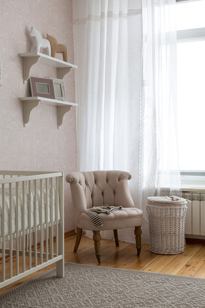 Idée de décoration pour une chambre de bébé fille tradition avec un mur rose, un sol en bois brun et un sol marron.